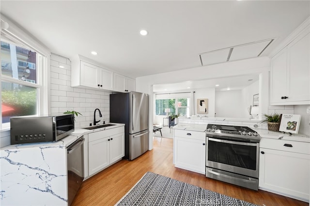 kitchen featuring appliances with stainless steel finishes, backsplash, light hardwood / wood-style floors, and white cabinetry