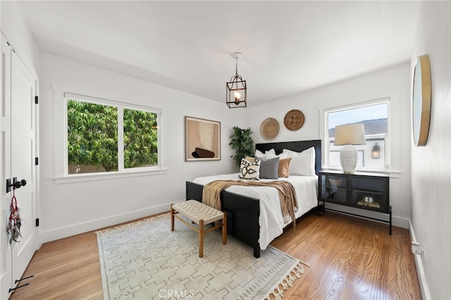 bedroom featuring light wood-type flooring and an inviting chandelier