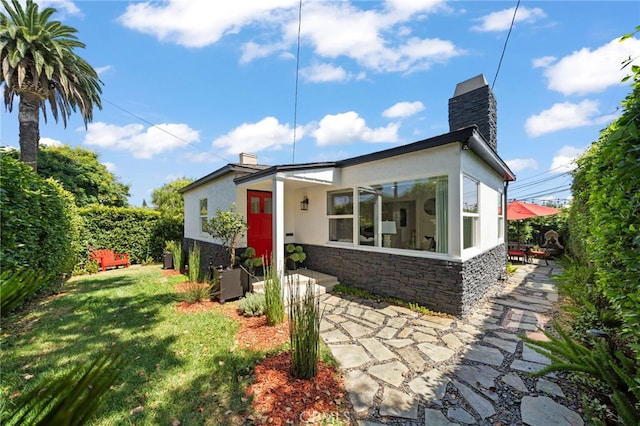 back of house with a lawn and a patio