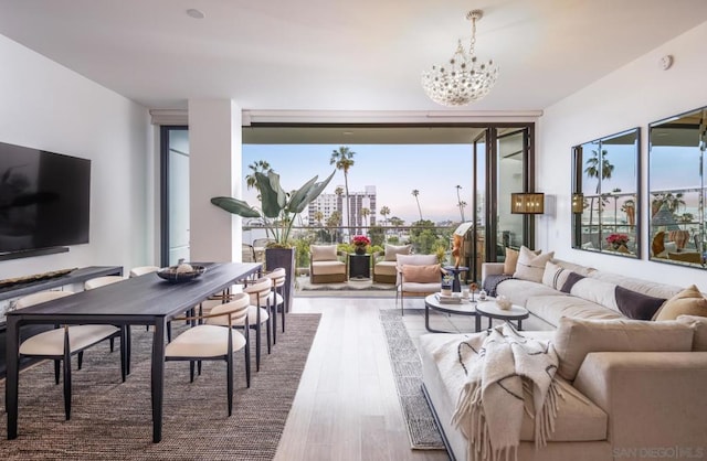 living room featuring an inviting chandelier, a healthy amount of sunlight, wood-type flooring, and expansive windows