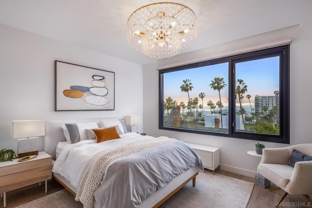 bedroom with hardwood / wood-style flooring, a water view, and an inviting chandelier