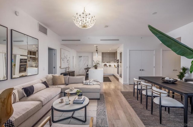 living room featuring light wood-type flooring and an inviting chandelier