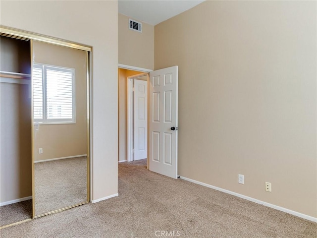 unfurnished bedroom with light carpet and a closet