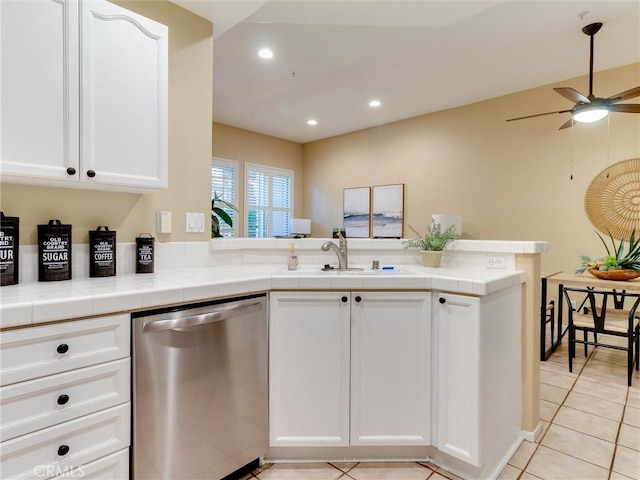 kitchen featuring sink, white cabinetry, tile countertops, stainless steel dishwasher, and kitchen peninsula