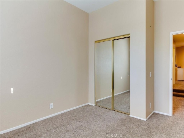 unfurnished bedroom with light carpet and a closet