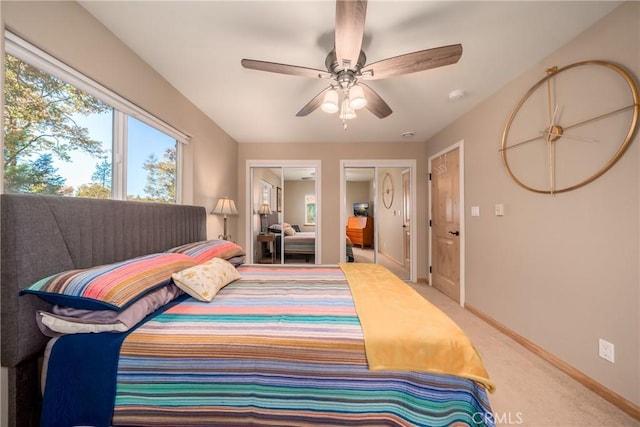 bedroom with ceiling fan, light colored carpet, and multiple closets