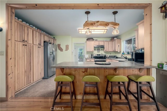 kitchen featuring kitchen peninsula, plenty of natural light, pendant lighting, light hardwood / wood-style floors, and appliances with stainless steel finishes