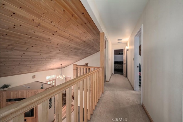 hallway with a chandelier, light colored carpet, and lofted ceiling