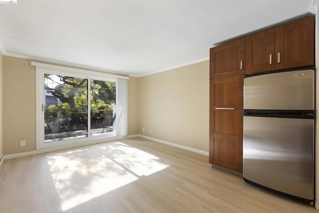 empty room featuring crown molding and light wood-type flooring