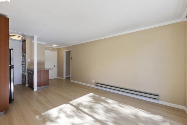 unfurnished room with baseboard heating, crown molding, and light hardwood / wood-style floors