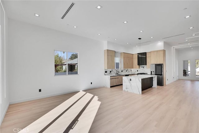 kitchen featuring a kitchen island, decorative light fixtures, sink, a kitchen bar, and stainless steel refrigerator with ice dispenser