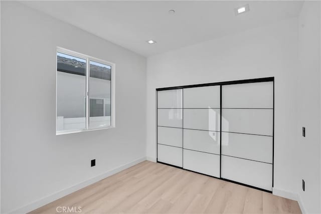 unfurnished bedroom featuring light wood-type flooring and a closet