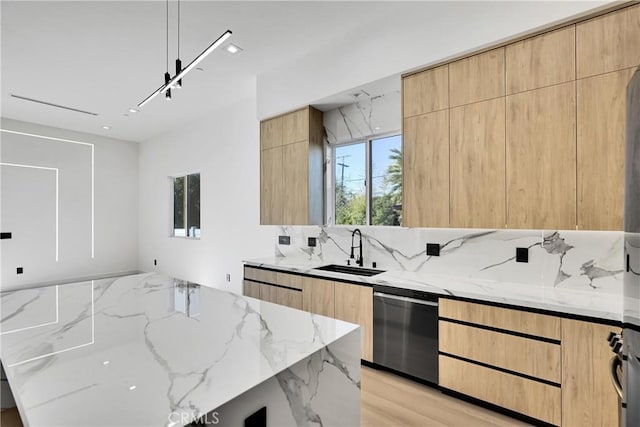 kitchen featuring light stone counters, sink, dishwasher, and light brown cabinets