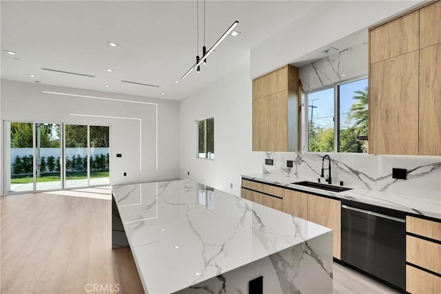 kitchen featuring a large island, sink, dishwasher, backsplash, and light stone counters