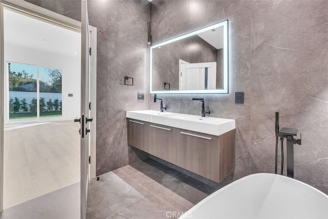 bathroom featuring vanity, tile walls, and a tub to relax in