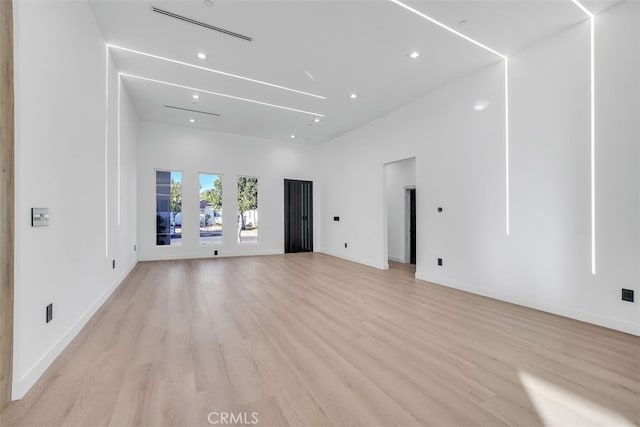 unfurnished living room with a high ceiling and light wood-type flooring