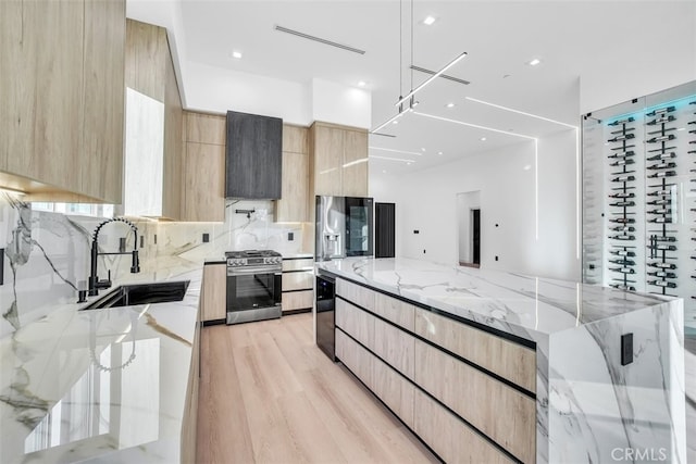 kitchen featuring light brown cabinetry, sink, light hardwood / wood-style flooring, appliances with stainless steel finishes, and light stone countertops