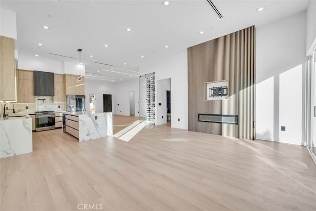 kitchen featuring sink, light brown cabinets, appliances with stainless steel finishes, pendant lighting, and light stone countertops