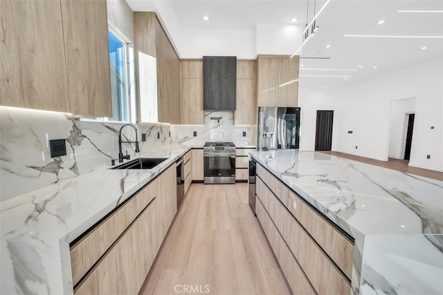 kitchen featuring light stone counters, appliances with stainless steel finishes, light brown cabinetry, and sink