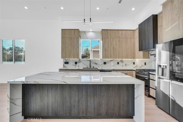 kitchen featuring light stone countertops, appliances with stainless steel finishes, a wealth of natural light, and decorative light fixtures