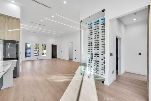 corridor with light hardwood / wood-style flooring and a high ceiling