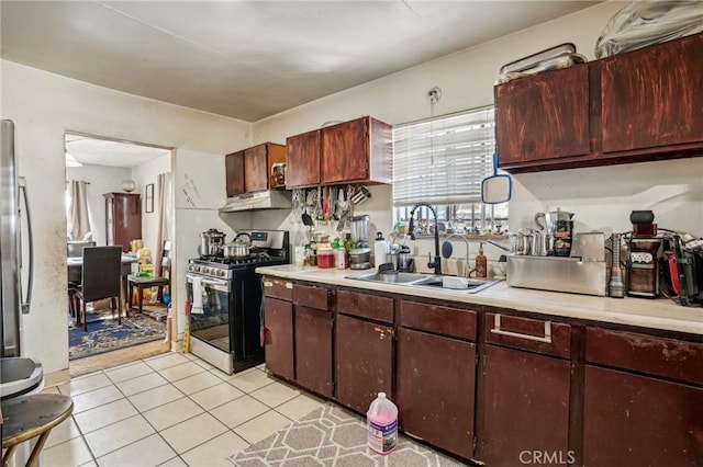 kitchen featuring stainless steel gas stove, dark brown cabinetry, light tile patterned floors, and sink