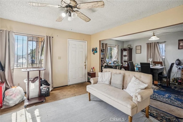 carpeted living room with ceiling fan and a textured ceiling