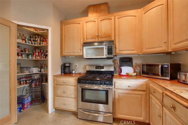 kitchen featuring wooden counters, light brown cabinetry, and stainless steel appliances