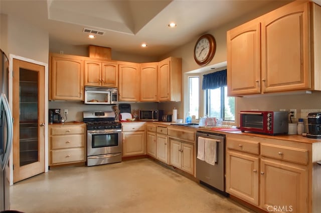 kitchen featuring a tray ceiling, light brown cabinetry, and stainless steel appliances