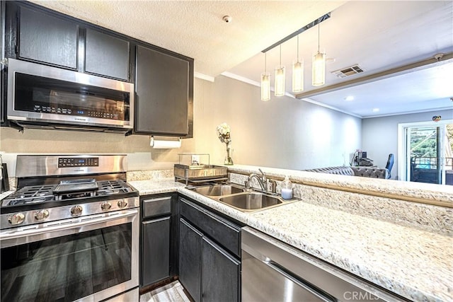 kitchen featuring appliances with stainless steel finishes, light stone counters, crown molding, sink, and pendant lighting