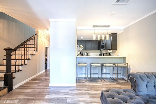 kitchen featuring crown molding, hanging light fixtures, dark hardwood / wood-style floors, kitchen peninsula, and stainless steel appliances