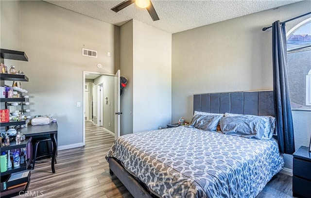 bedroom with hardwood / wood-style flooring, ceiling fan, and a textured ceiling