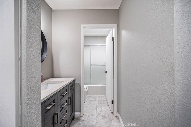 full bathroom featuring vanity, toilet, and shower / bath combination with glass door