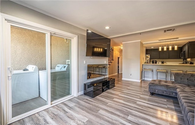 living room with separate washer and dryer, light hardwood / wood-style flooring, and ornamental molding