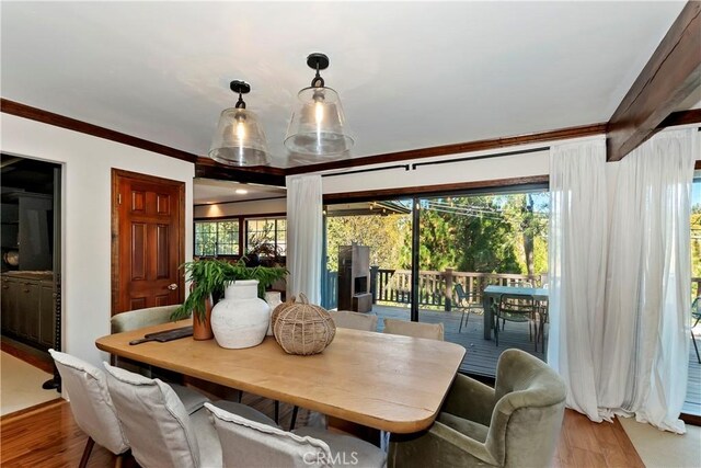 dining room with light wood-type flooring, ornamental molding, and a healthy amount of sunlight