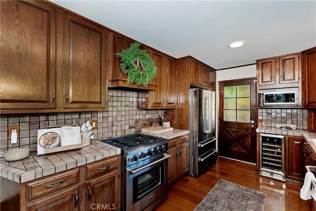 kitchen with tile counters, dark hardwood / wood-style floors, backsplash, wine cooler, and high end appliances