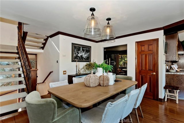 dining area with dark wood-type flooring and crown molding