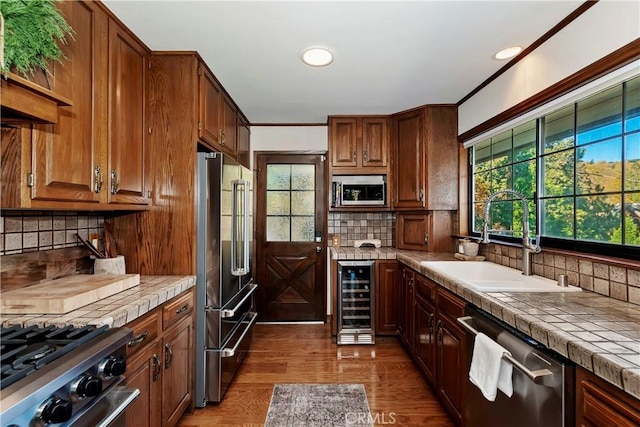 kitchen with beverage cooler, stainless steel appliances, tasteful backsplash, sink, and tile countertops