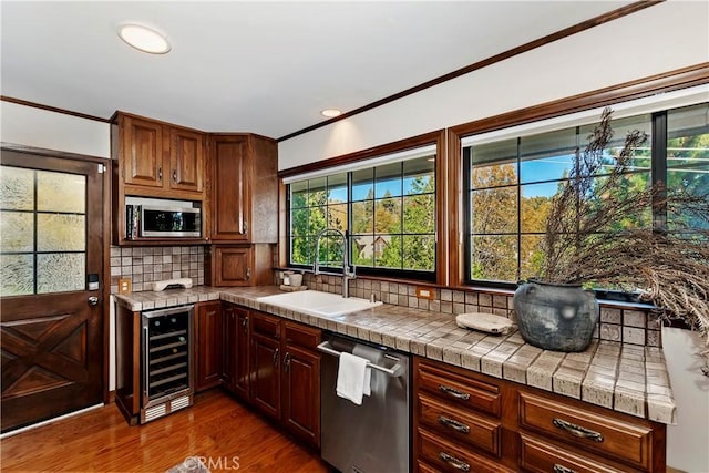 kitchen featuring appliances with stainless steel finishes, backsplash, dark hardwood / wood-style flooring, beverage cooler, and sink