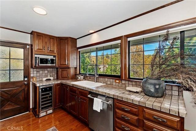 27538 W Shore Rd, Lake Arrowhead, CA 92352 - kitchen featuring beverage cooler, a sink, stainless steel appliances, ornamental molding, and dark wood finished floors