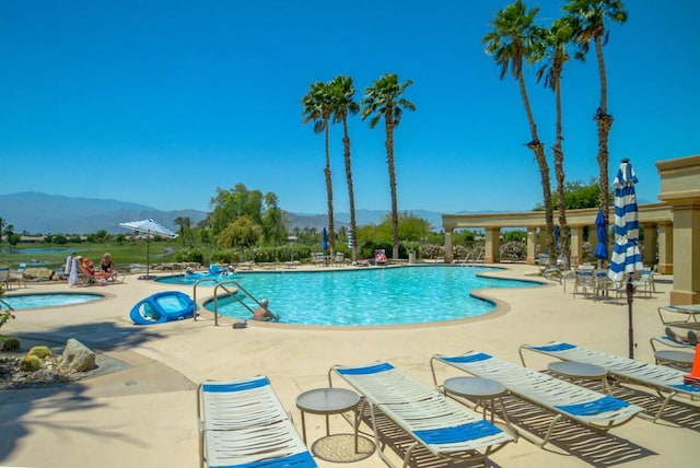 view of pool featuring a patio area, a mountain view, and a hot tub