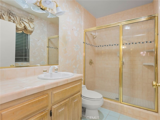 bathroom featuring tile patterned flooring, vanity, toilet, and a shower with shower door