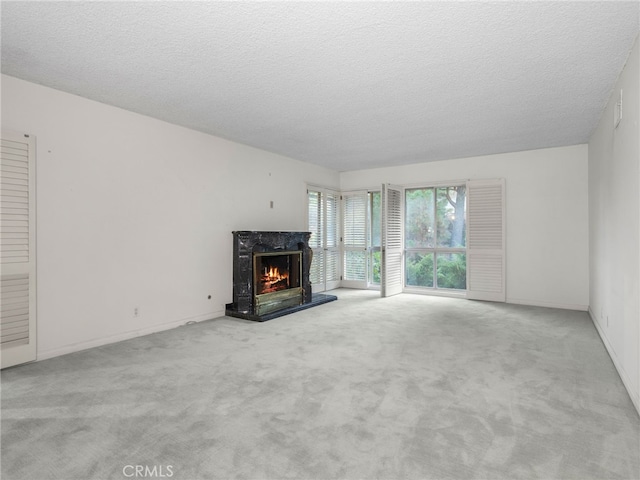 unfurnished living room with a textured ceiling, light colored carpet, and a fireplace