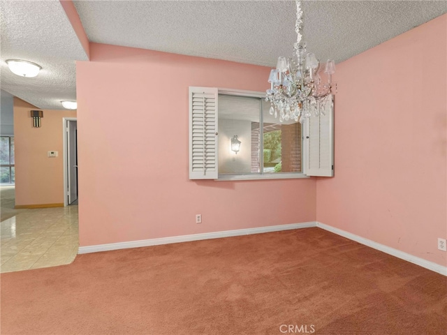 carpeted spare room featuring a textured ceiling and an inviting chandelier