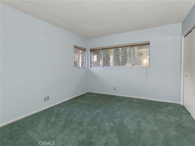 unfurnished room featuring dark carpet and a textured ceiling