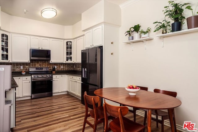 kitchen with appliances with stainless steel finishes, tasteful backsplash, ornamental molding, dark hardwood / wood-style floors, and white cabinetry