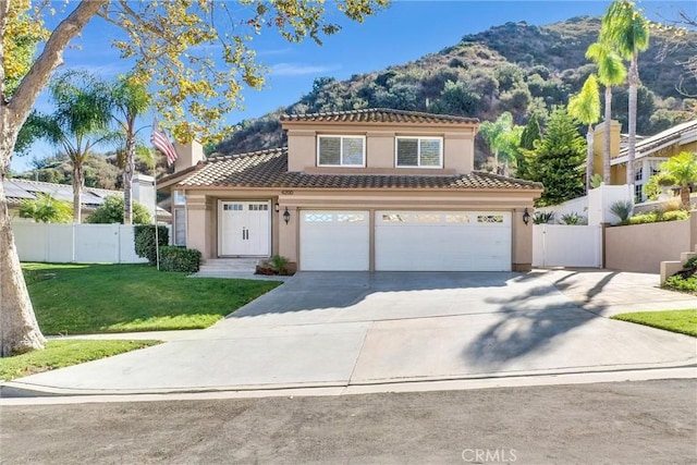 mediterranean / spanish house with a mountain view, a garage, and a front yard