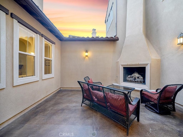 patio terrace at dusk with an outdoor living space with a fireplace