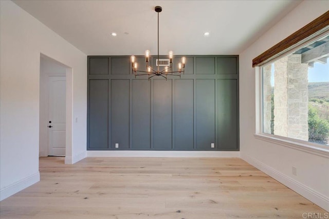 unfurnished dining area with light hardwood / wood-style floors and a notable chandelier