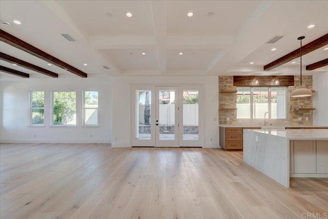 kitchen with beam ceiling, light hardwood / wood-style flooring, hanging light fixtures, and a healthy amount of sunlight